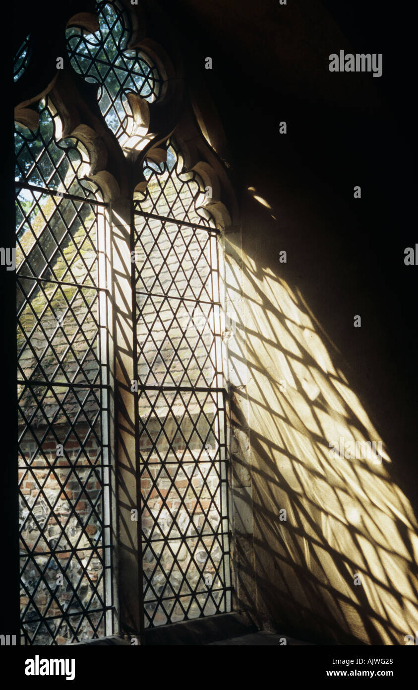 Un diamante piombata la finestra della chiesa getta un' ombra sul suo interno alcova con una vista del portico e un albero al di là Foto Stock