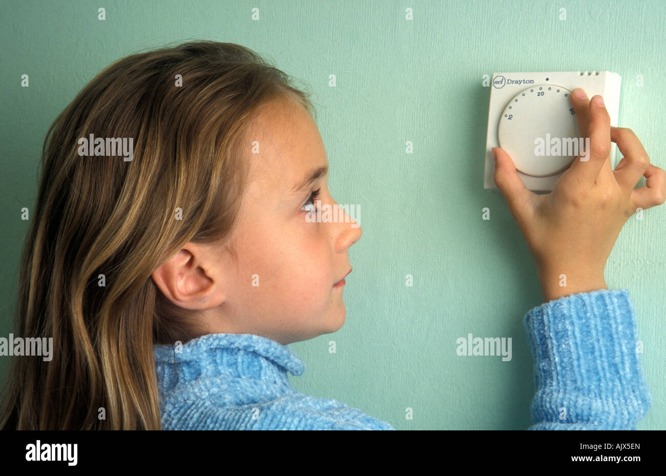 Giovane ragazza termostato di regolazione sulla parete per il riscaldamento centrale Foto Stock