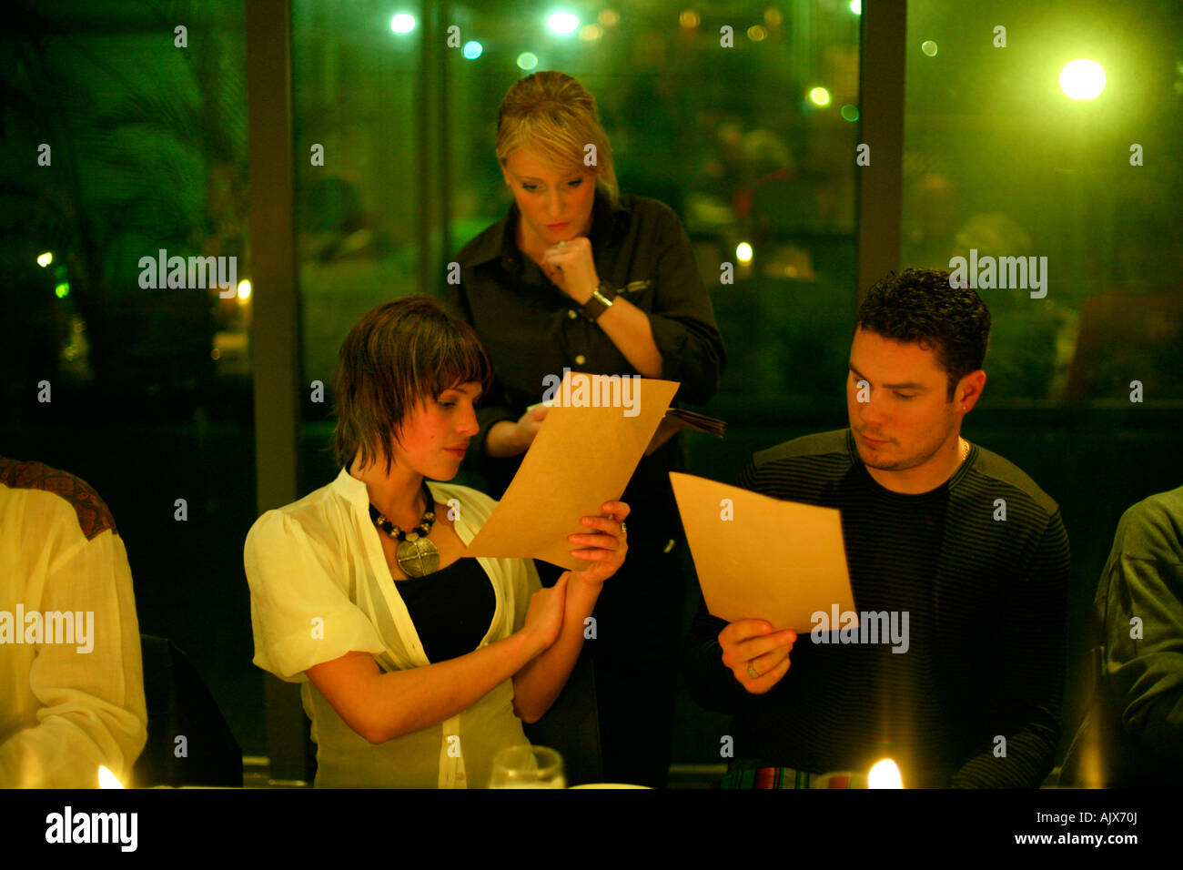 Una giovane coppia ordinare un pasto dal menu mentre la cameriera offre consulenza presso un ristorante a Sydney in Australia Foto Stock