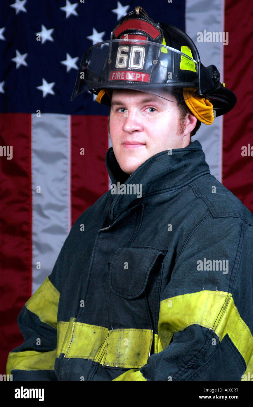 Giovane Fire Fighter ritratto in posa davanti alla bandiera americana Foto Stock