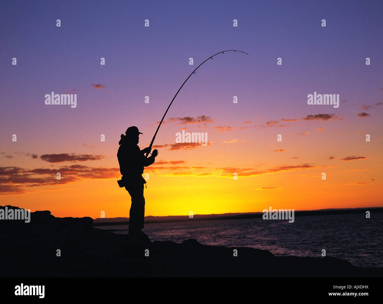 Lo stile di vita, Sport, Uomo pesca dalle rocce, al tramonto, Foto Stock