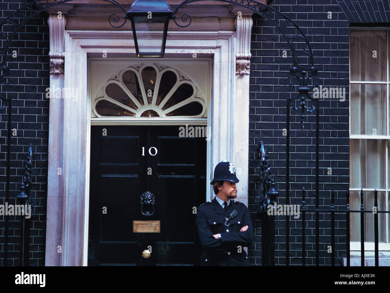 Regno Unito. In Inghilterra. Londra. Poliziotto in piedi davanti alla porta del numero dieci, Downing Street. Foto Stock