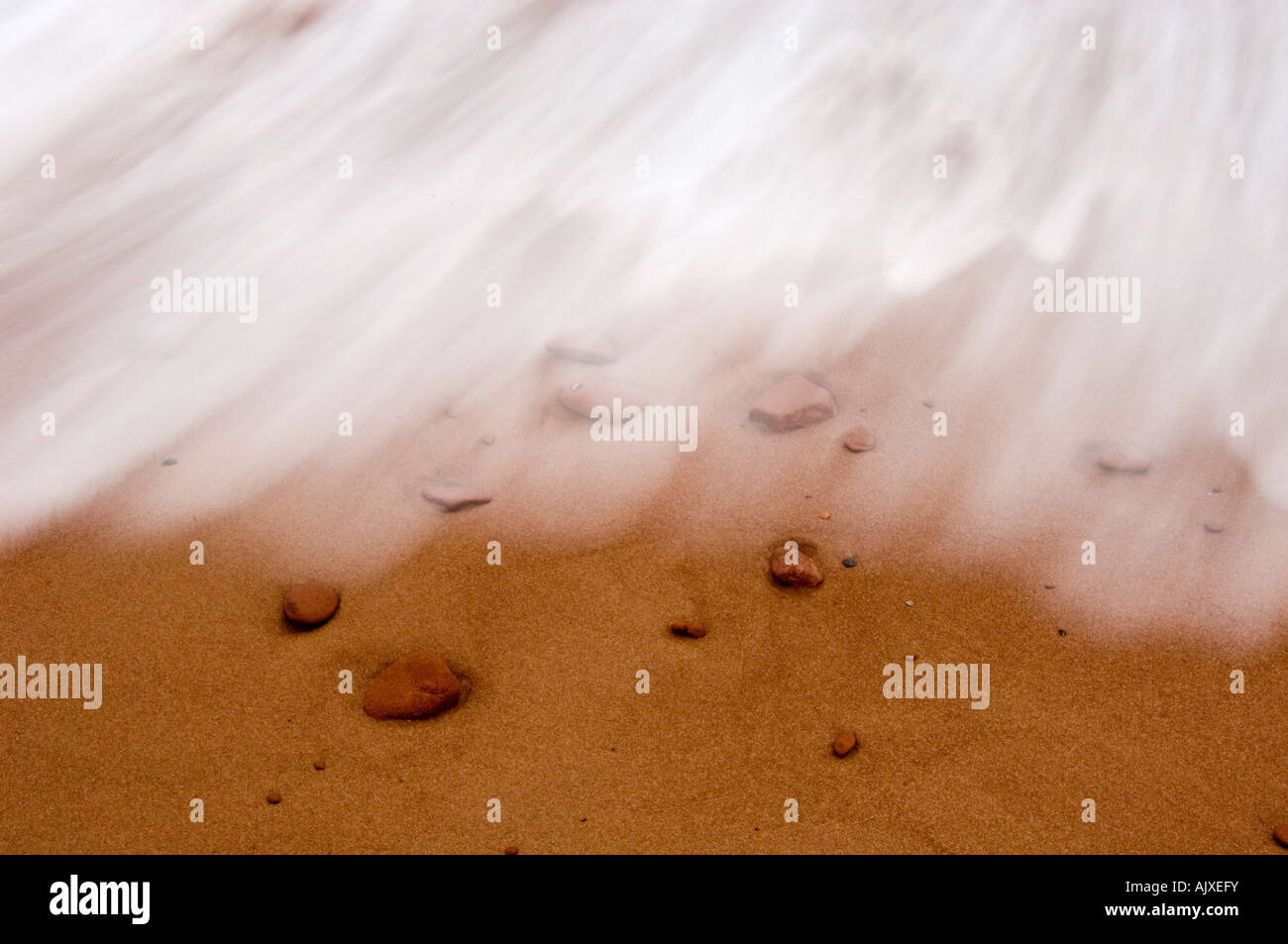 Spiaggia di sabbia e rocce rosse con la luce in entrata surf runoff patterns, Campbell's Cove, PE/PEI, Canada Foto Stock