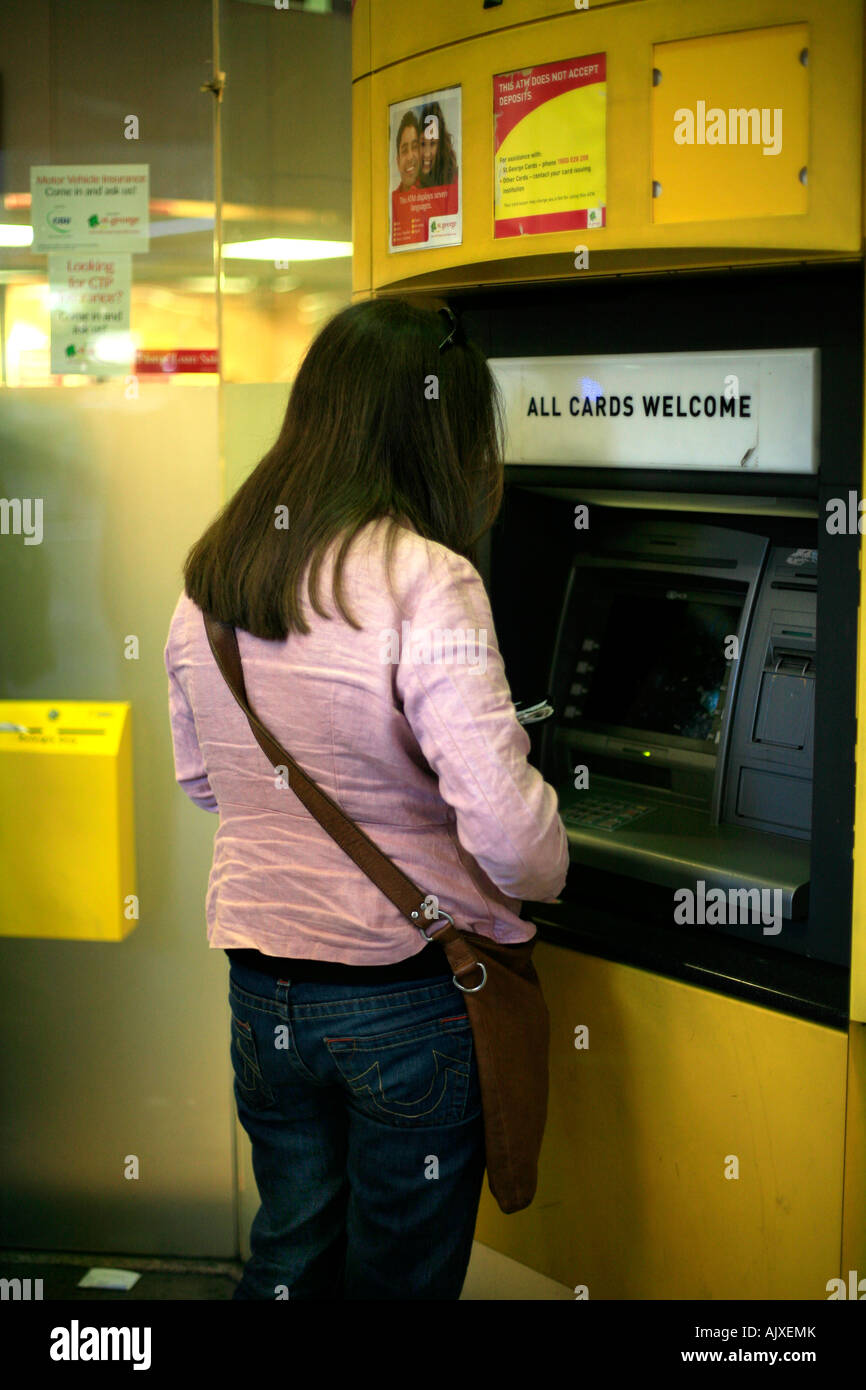 Una donna usa un bancomat al di fuori di una banca Foto Stock Una donna usa un bancomat al di fuori di una banca Foto Stock