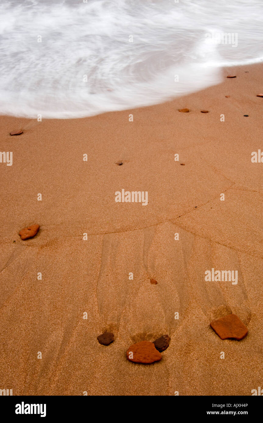 Spiaggia di sabbia e rocce rosse con la luce in entrata surf runoff patterns, Campbell's Cove, PE/PEI, Canada Foto Stock