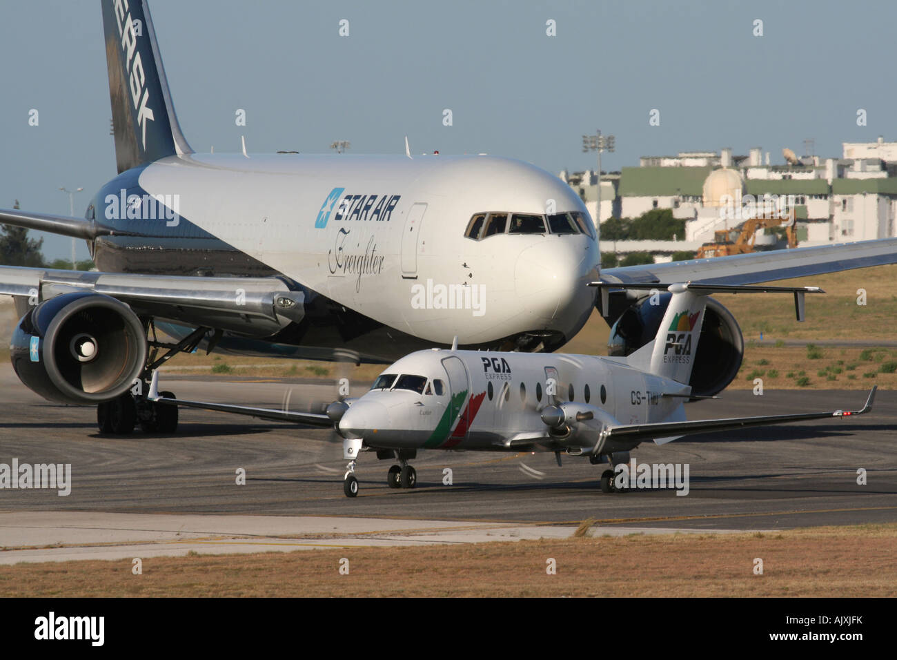 Traffico aereo. Coda degli aerei per il decollo all'aeroporto di Lisbona. Un PGA Beech 1900D si allinea sulla pista mentre un jet Star Air Boeing 767 attende il suo turno. Foto Stock