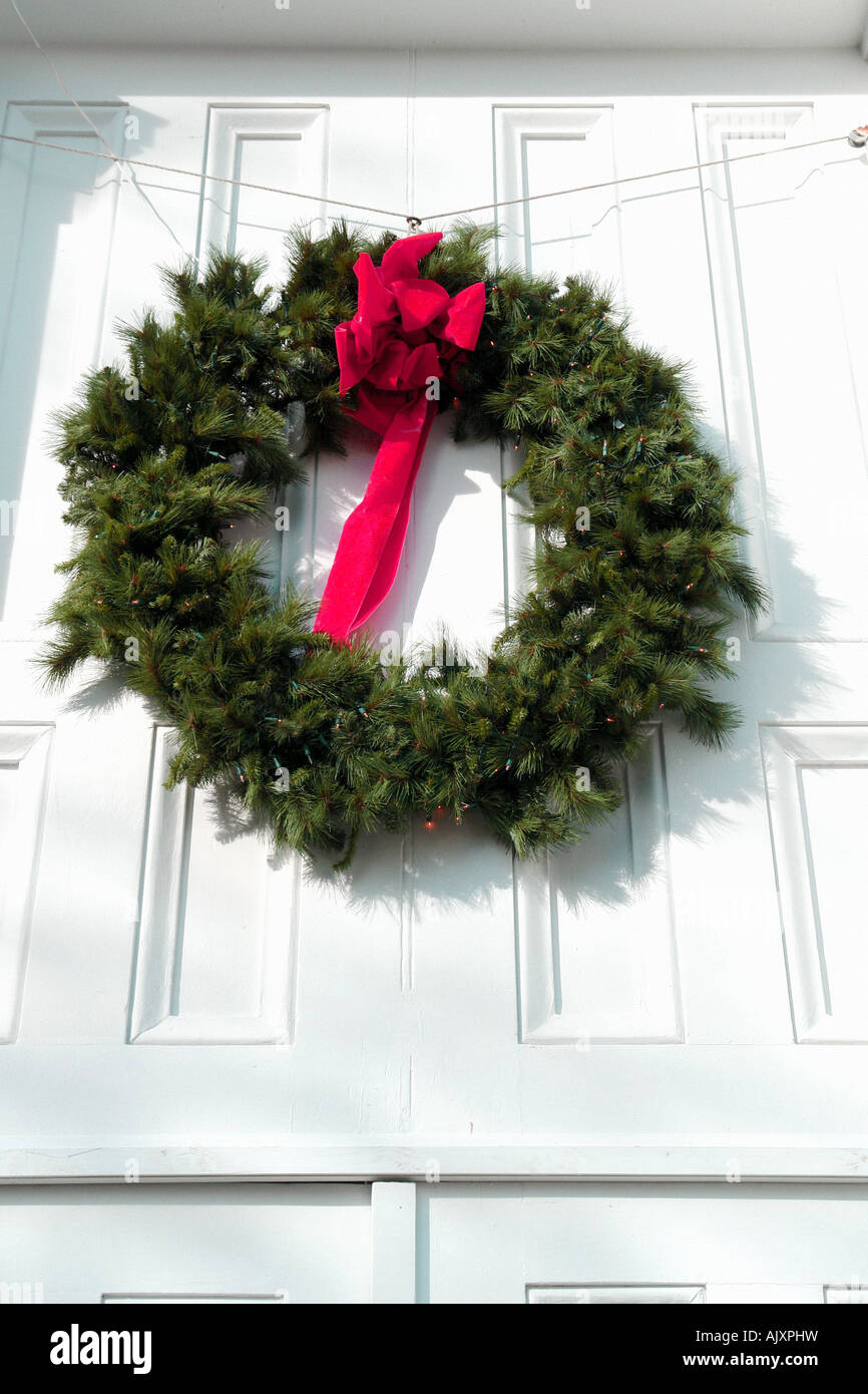 Holiday Ghirlanda di Natale con Red Velvet Ribbon Bow sulla porta bianca Foto Stock