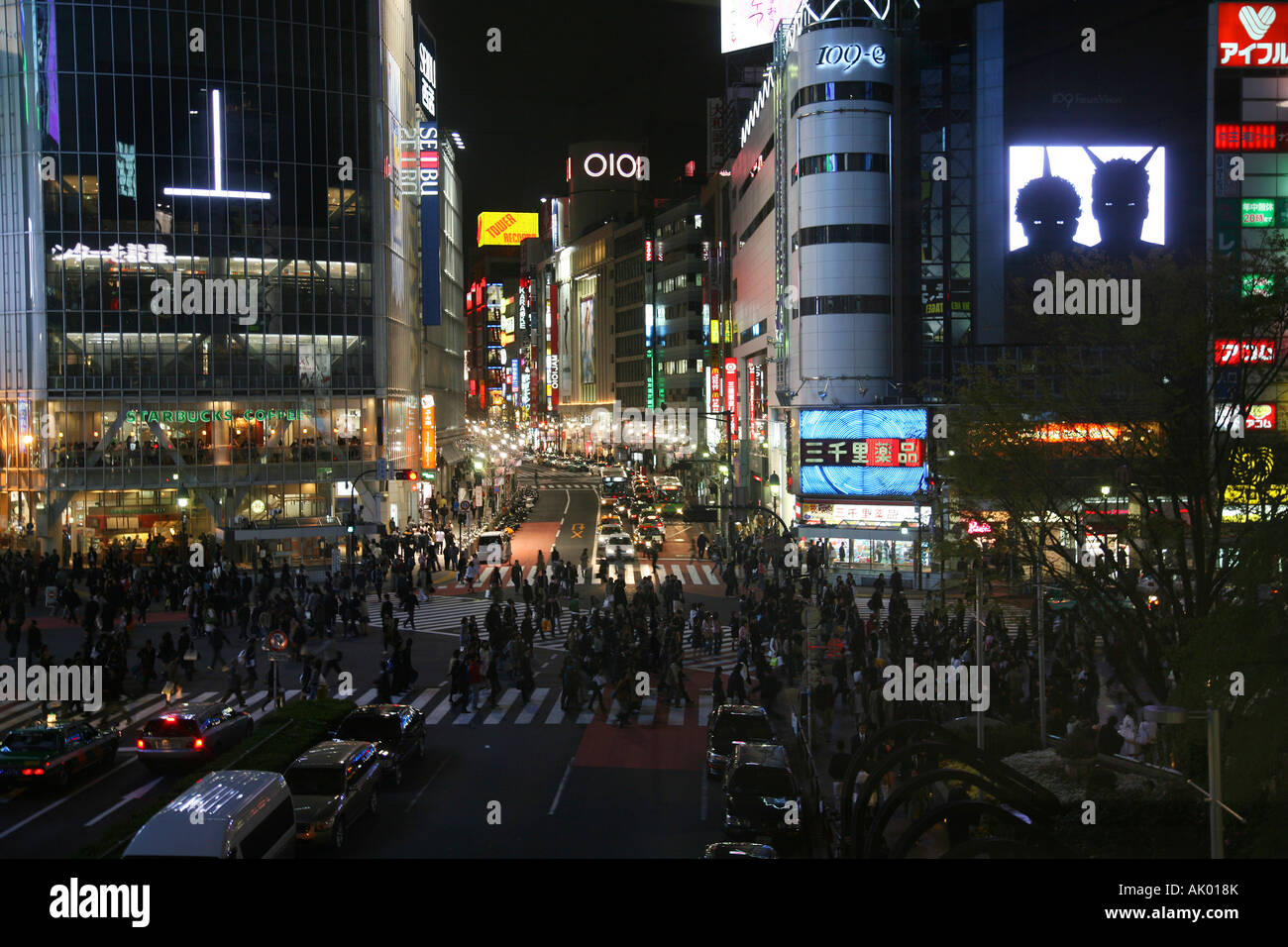 Vista notturna dalla stazione di Shinjuku a Tokyo del traffico e le persone che attraversano la strada Foto Stock