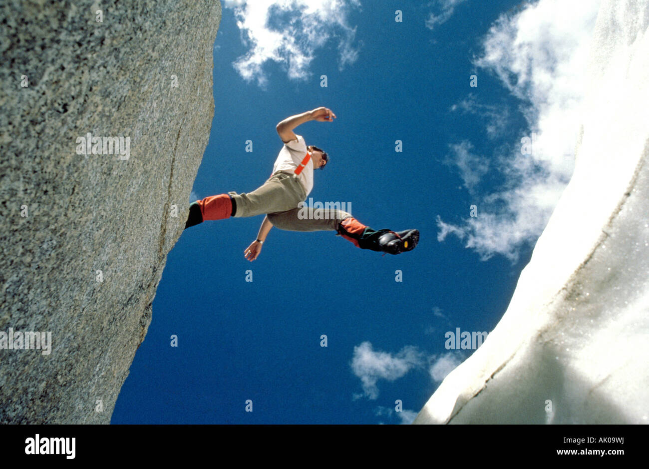 Un escursionista salta sopra un crepaccio su un ghiacciaio alto nelle Montagne Rocciose Canadesi nel Parco Nazionale di Banff Foto Stock