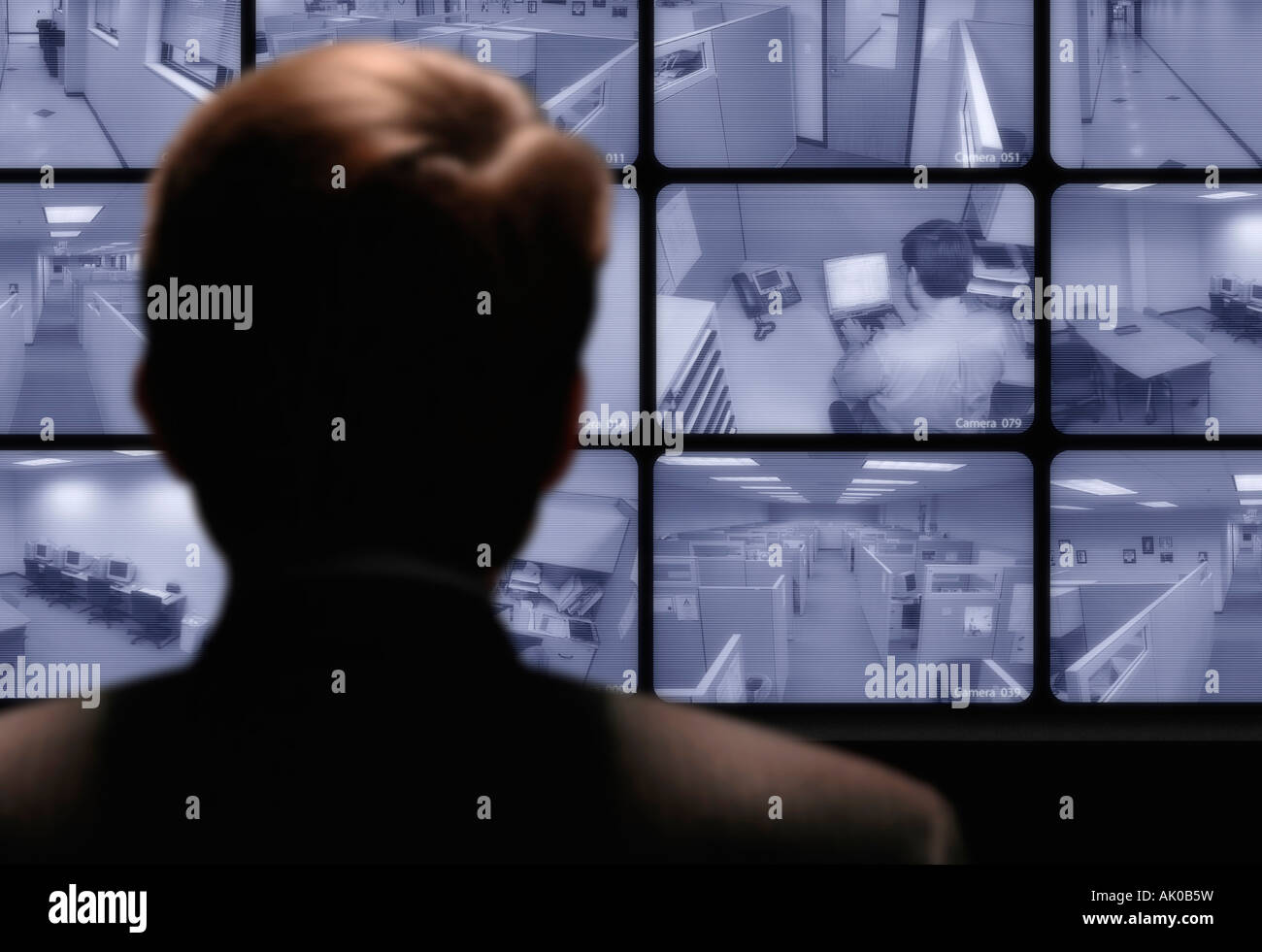 Sorveglianza video uomo guardando un lavoro dipendente attraverso un circuito chiuso di un monitor video Foto Stock