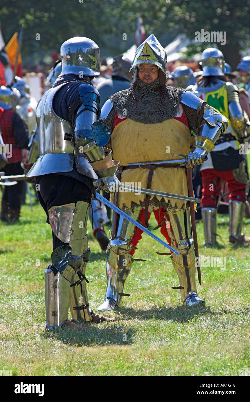 Due uomini in abiti di armatura scintillante facendo battaglia con ogni altro alla rievocazione medievale Foto Stock