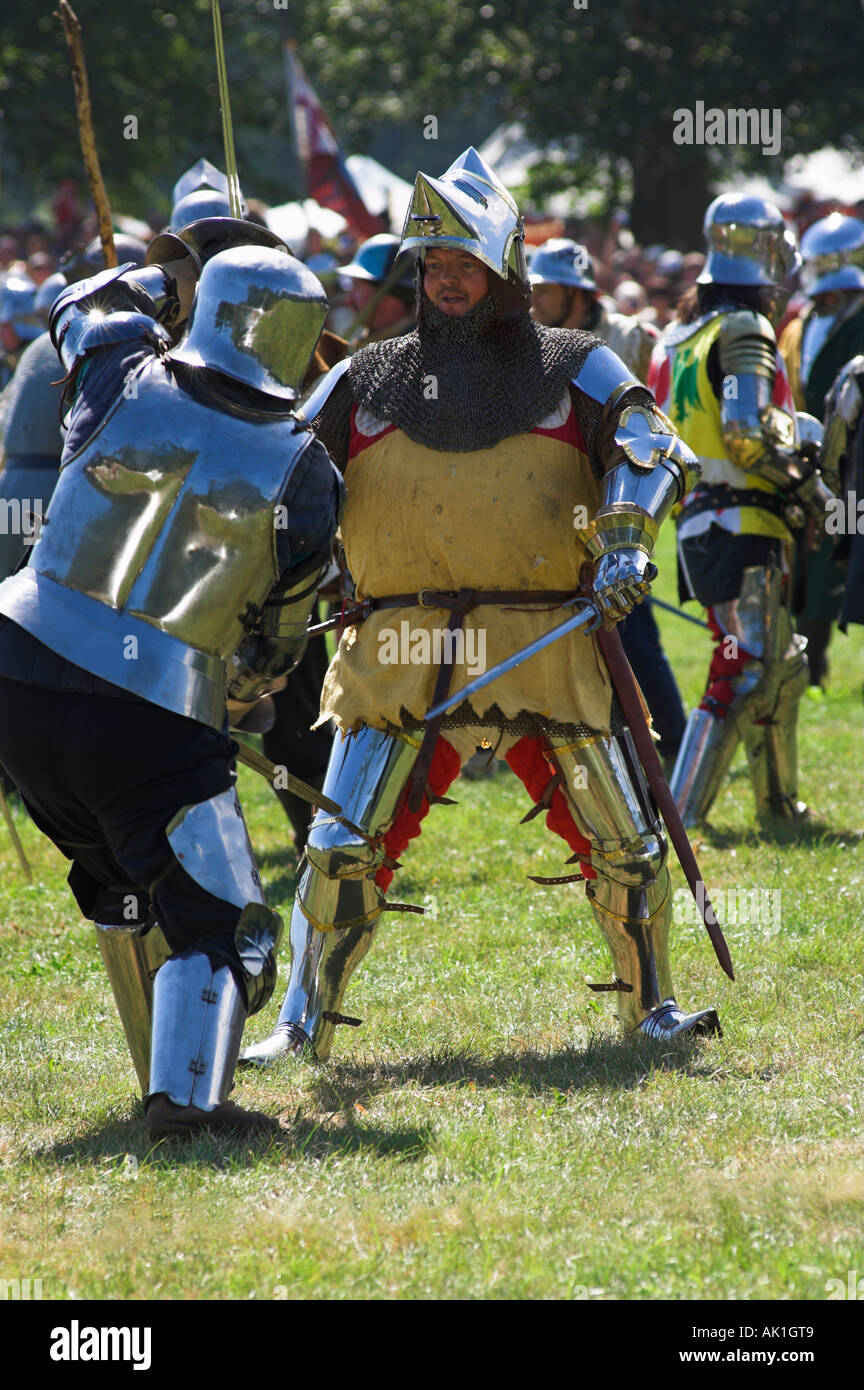 Due uomini in abiti di armatura scintillante facendo battaglia con ogni altro alla rievocazione medievale Foto Stock