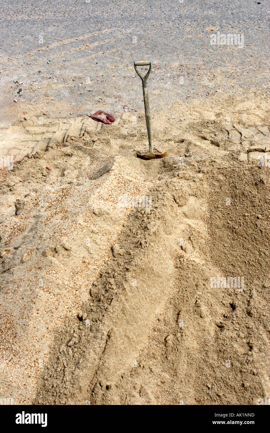 Pala di costruttori integrati in sabbia con scartato guanto di gomma Foto Stock