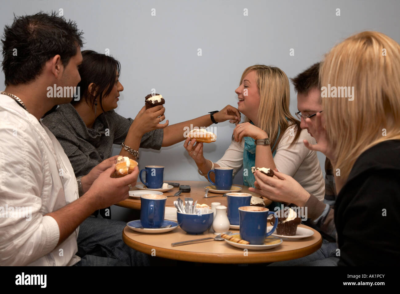 Il gruppo di cinque studenti seduti in un caffè gustando una tazza di caffè e alcune focacce Foto Stock