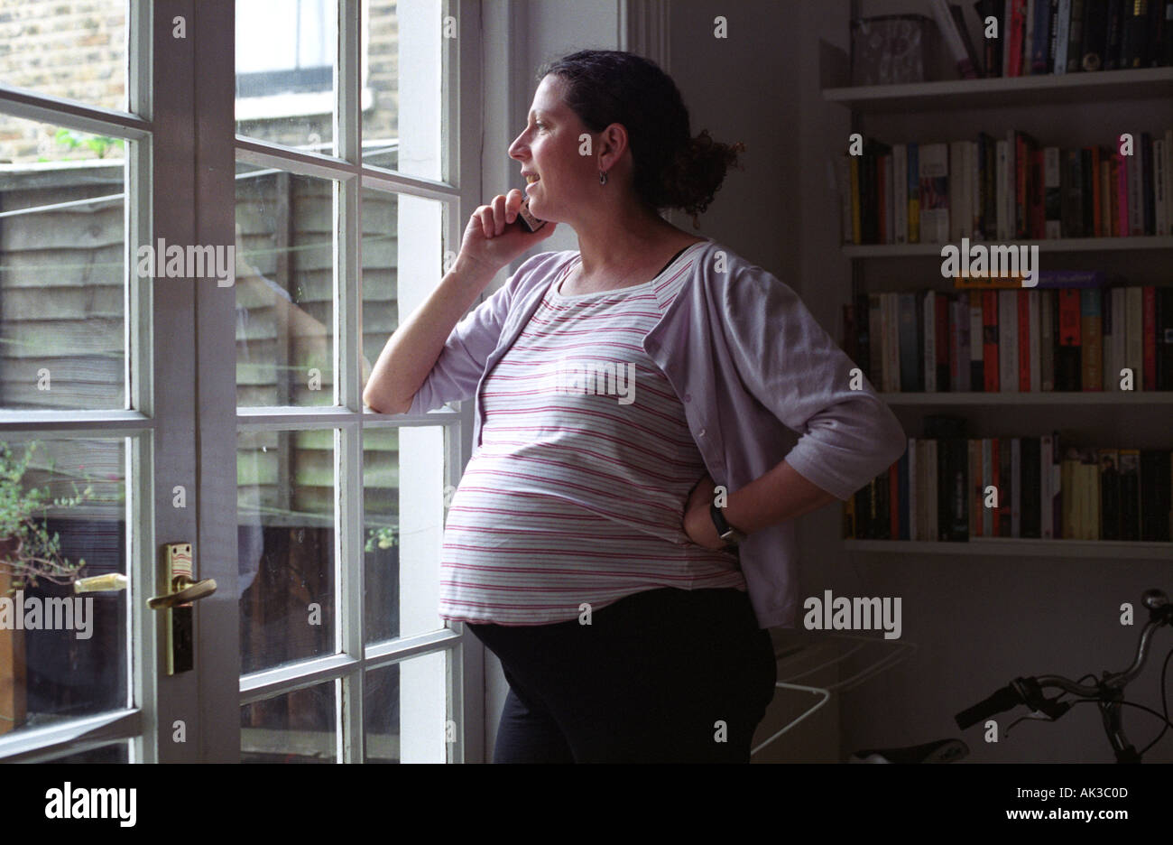 Una donna incinta sul telefono in casa, Londra, Regno Unito. Foto Stock
