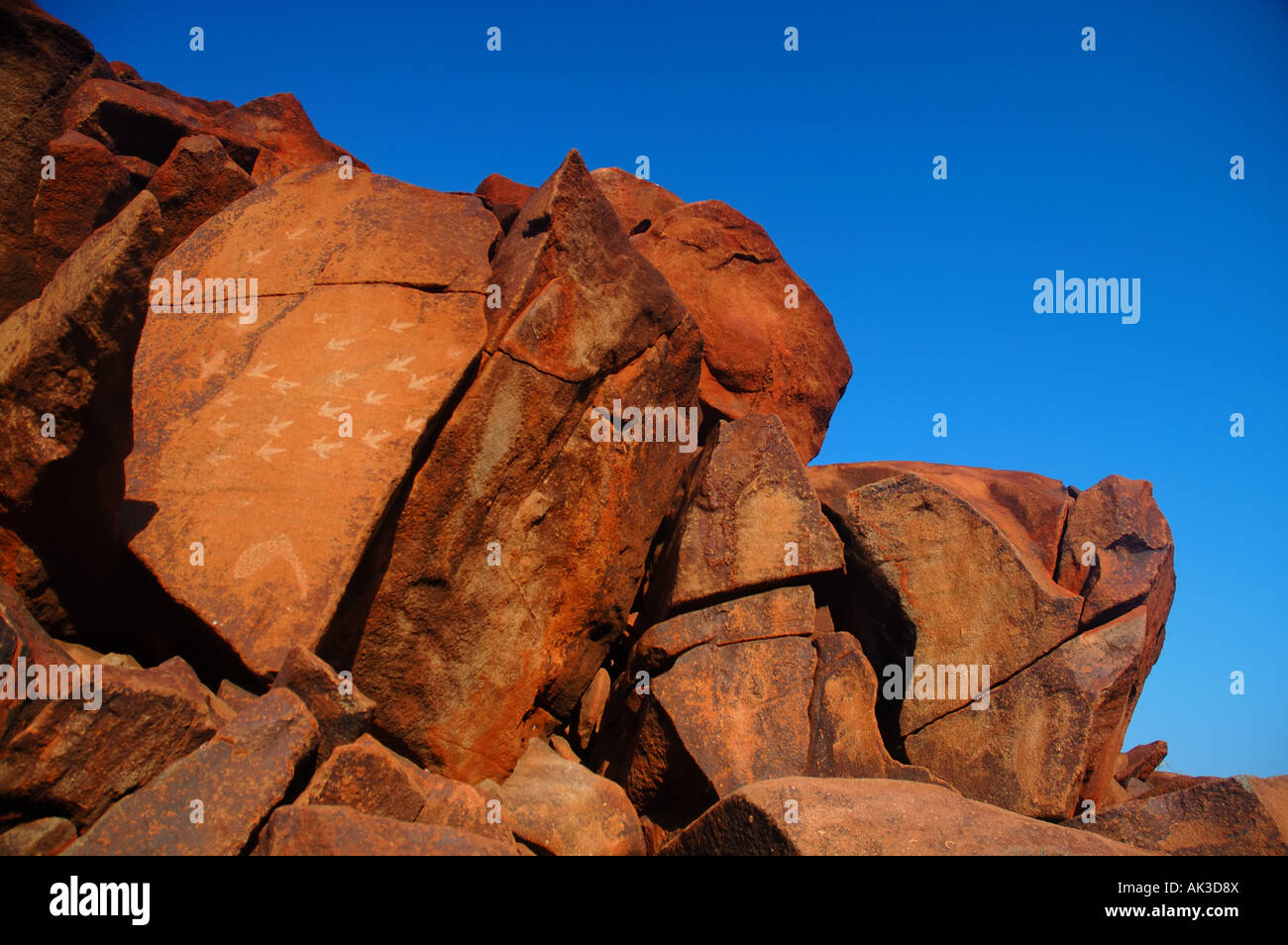 Tracce di uccelli incisi nella pietra antica arte rupestre degli Aborigeni in corrispondenza di una gola profonda, penisola di Burrup, Australia occidentale Foto Stock