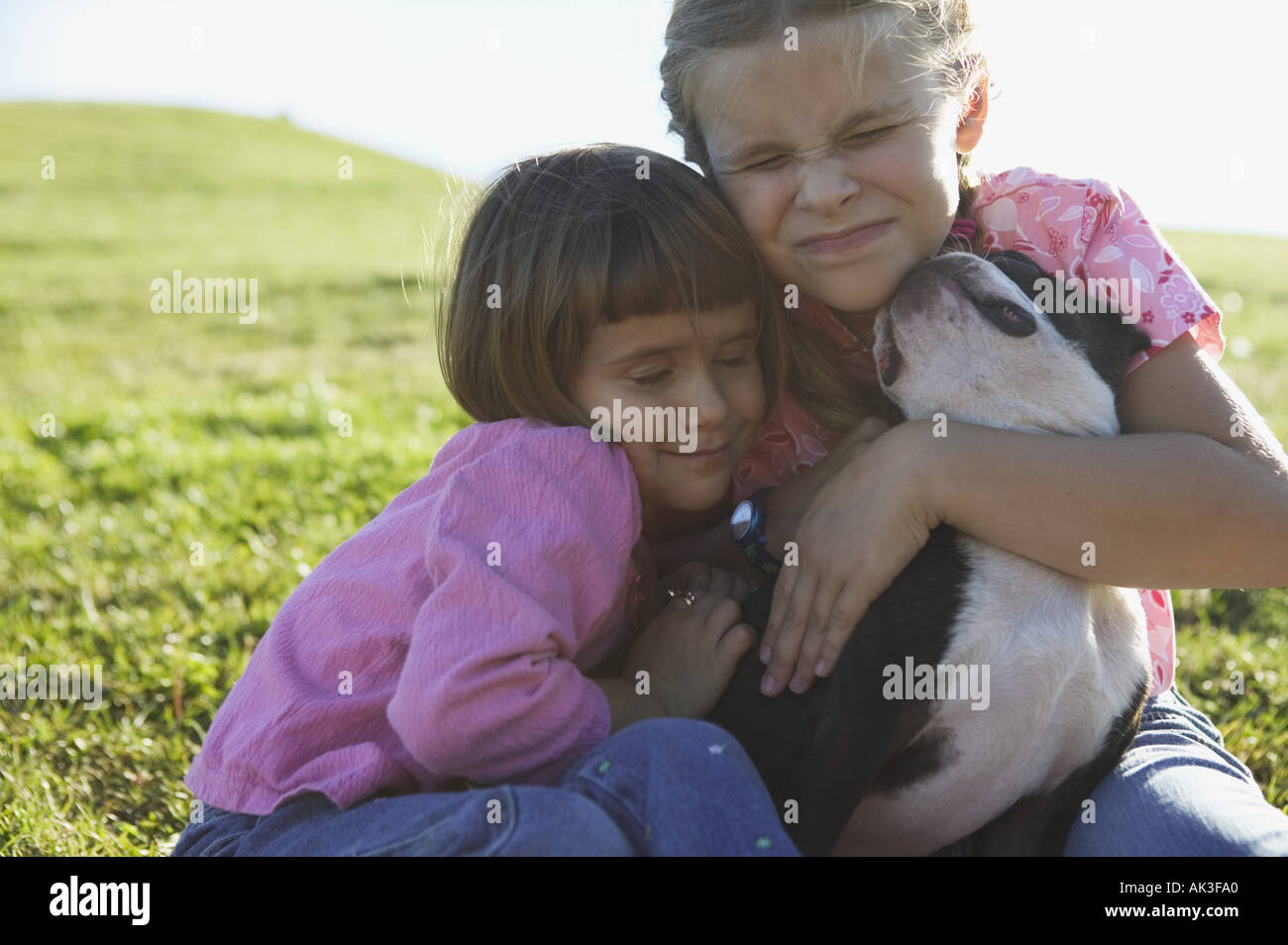 Due ragazze abbracciando il loro cane Foto Stock