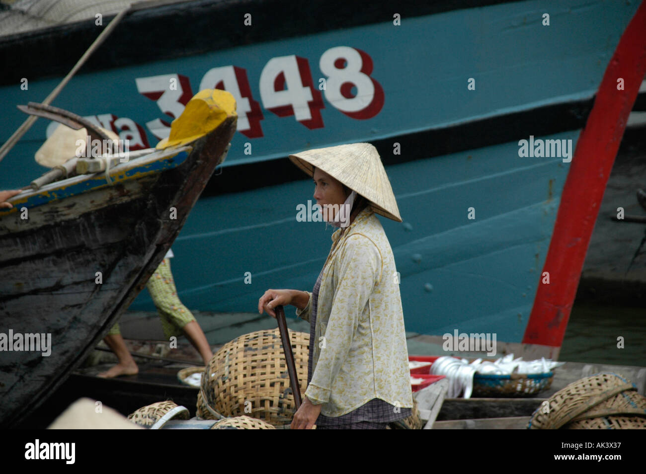 Donna che indossa un cono a forma di cappello sorge tra barche Hoi An Vietnam Foto Stock
