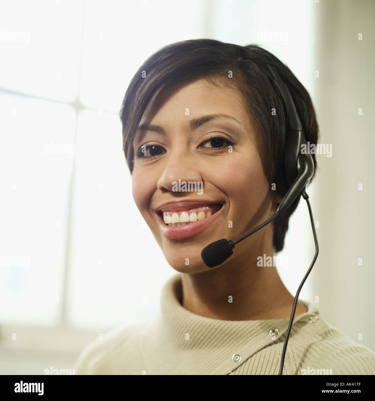 Ritratto di un sorridente multi etnico donna 30s indossare una cuffia telefonica Foto Stock