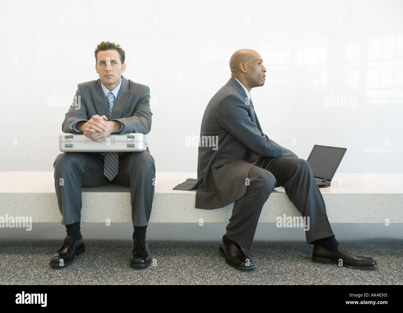 Sul banco, un imprenditore seduto con valigetta sul giro, secondo uomo d affari con computer portatile Foto Stock