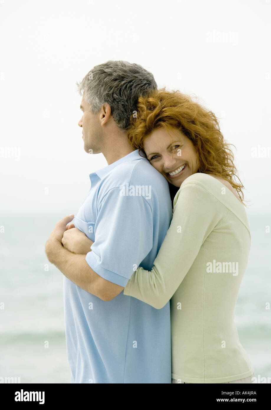 Donna Uomo che abbraccia da dietro, mare in background Foto stock - Alamy