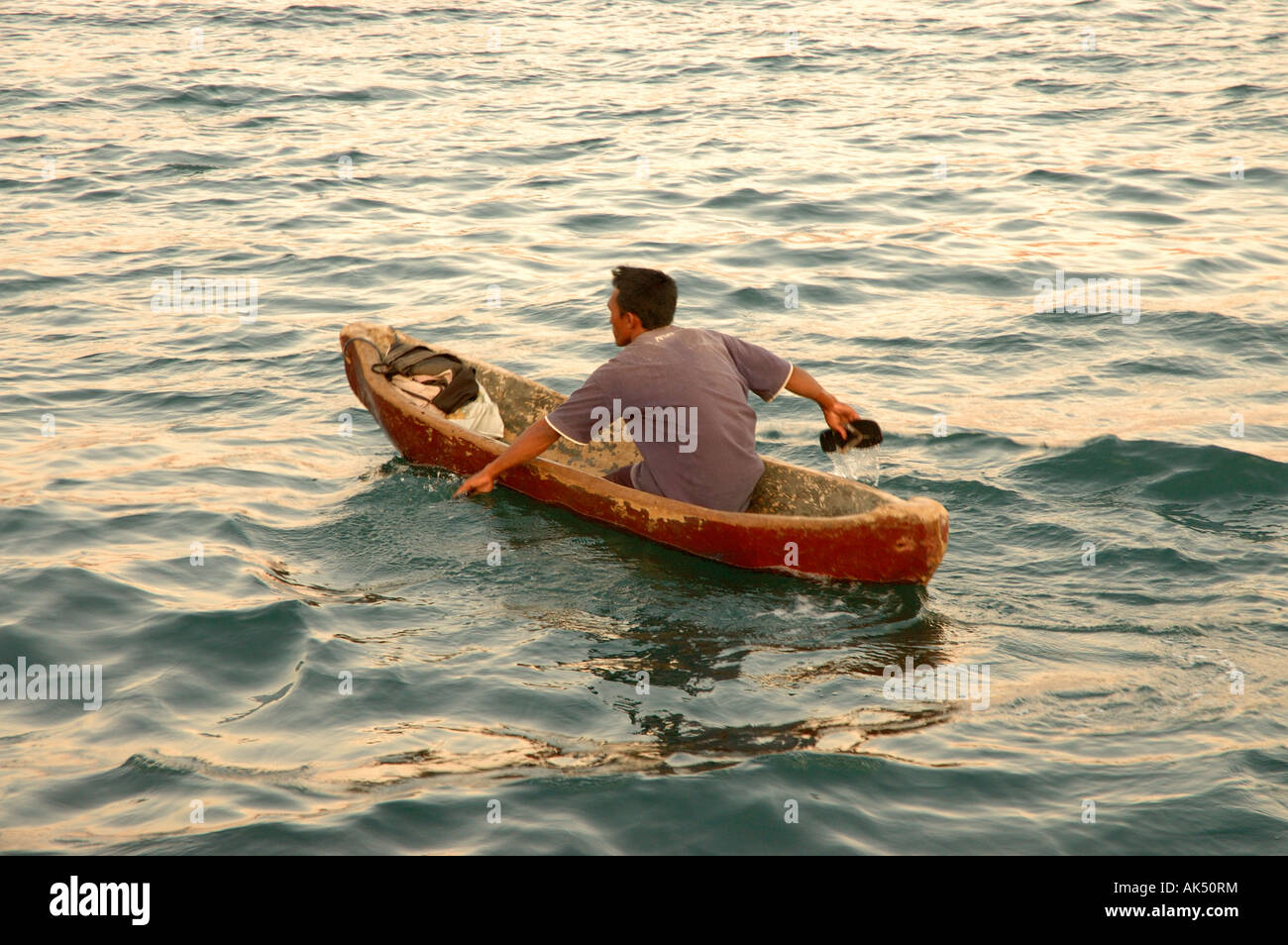 Un uomo in Indonesia paddling una canoa con la sua flip flop Foto Stock