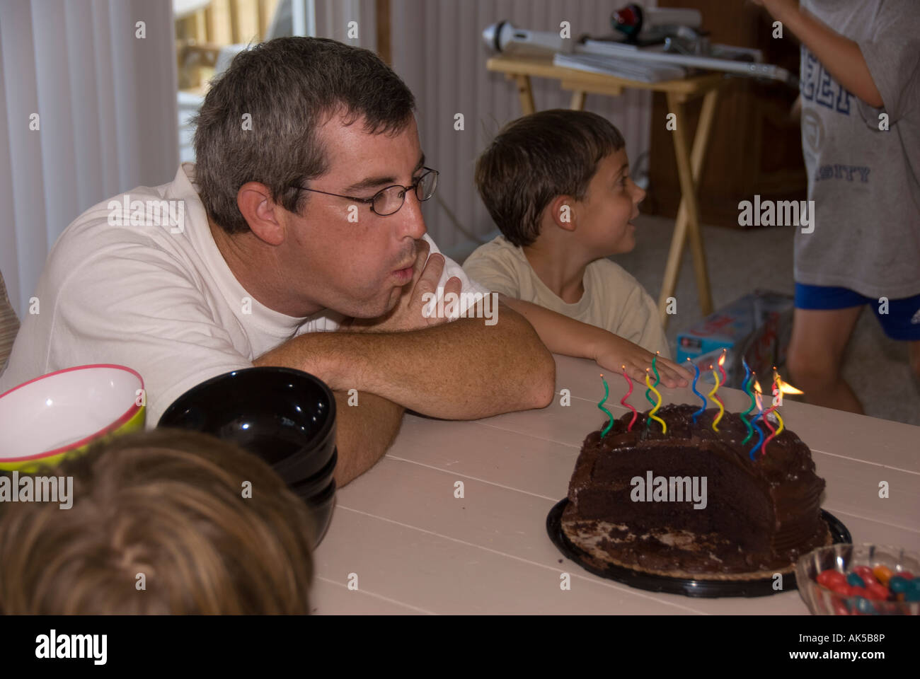 Festa di compleanno, papà si brucia candele sul cioccolato torta di compleanno Foto Stock