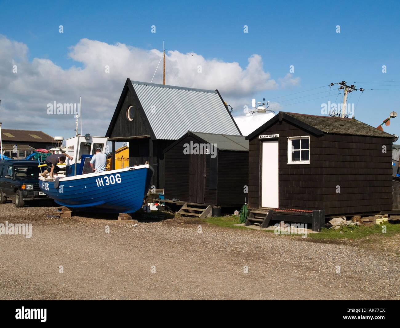 Pescatore in legno capanne e una blu barca da pesca a Southwold harbour Suffolk Foto Stock