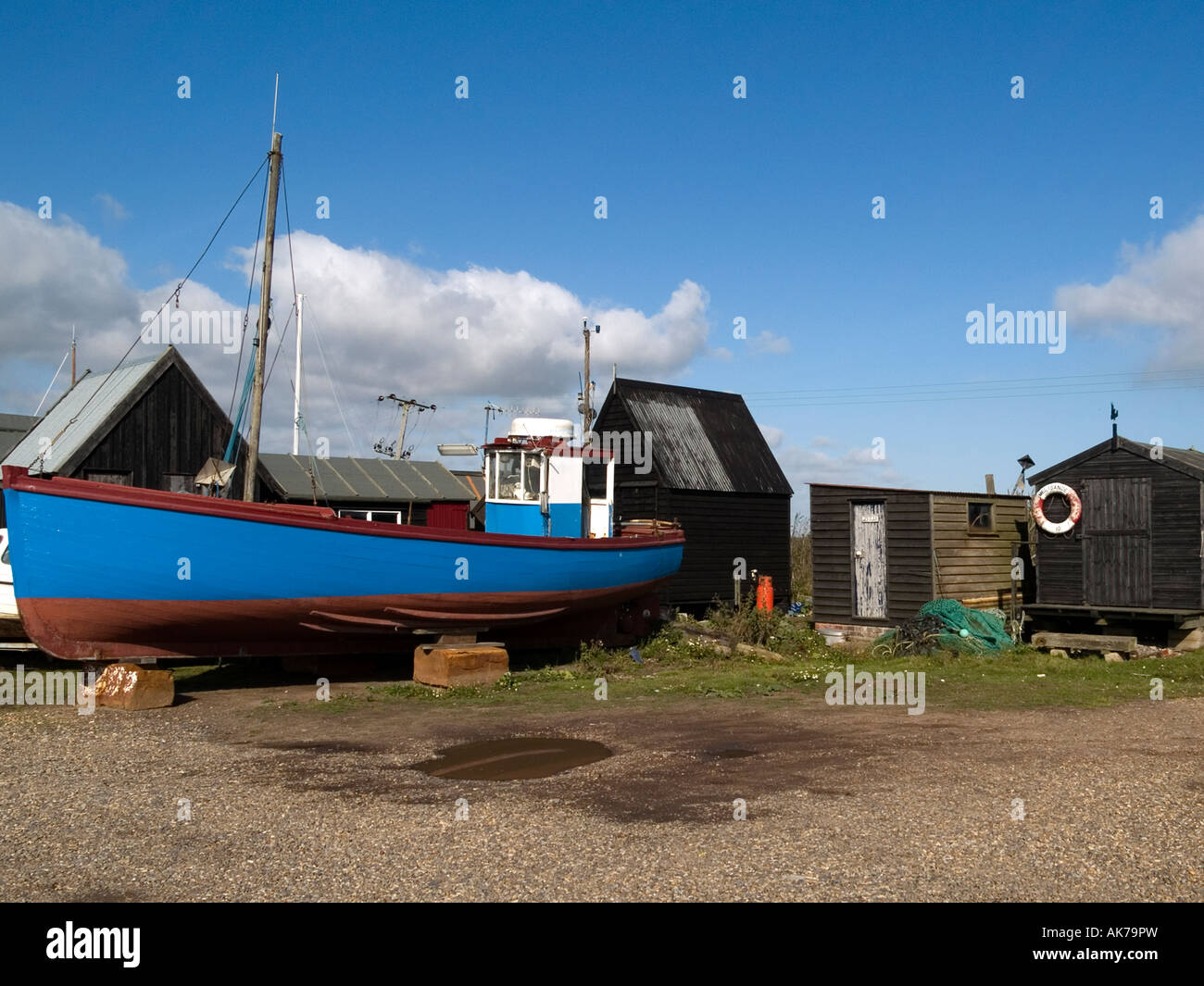 In legno di capanne di pescatori e una blu barca da pesca a Southwold harbour Suffolk, Inghilterra, Regno Unito Foto Stock