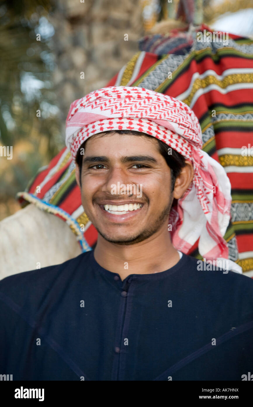 Cultura araba, sorridente giovane cammello arabo driver con decorate cammello arabo presso l'albergo, Emirati arabi uniti, Foto Stock