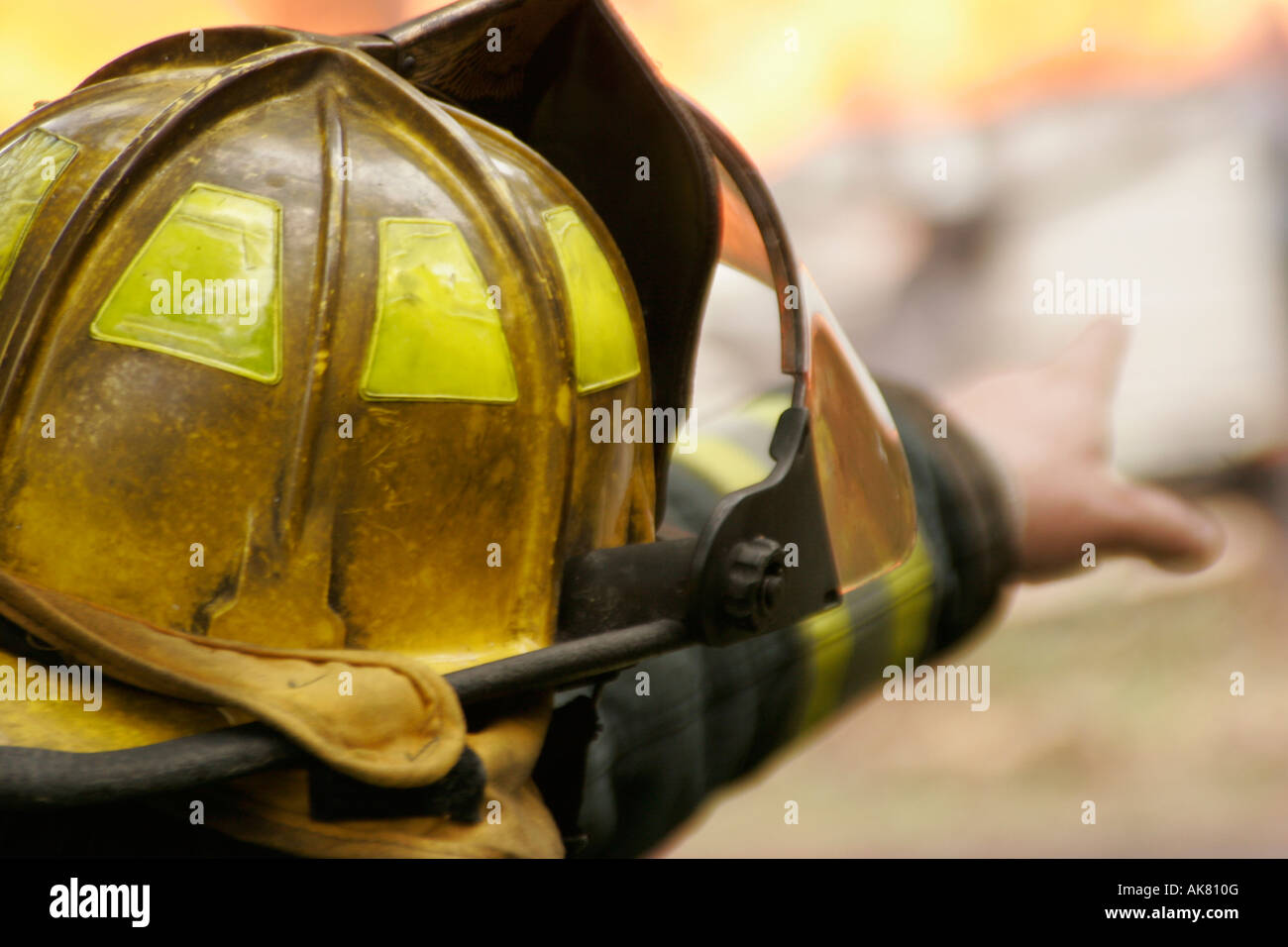 Vigile del fuoco nel casco giallo rivolta ad una casa di fuoco Foto Stock