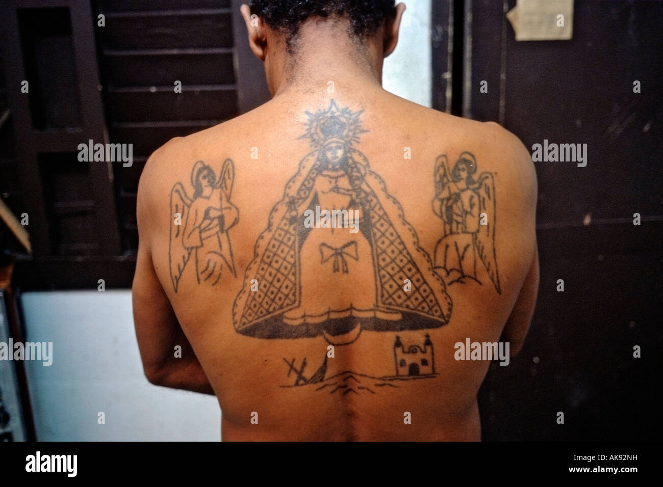 Tatuaggio con il simbolismo religioso sul retro dell uomo cubano. Foto Stock