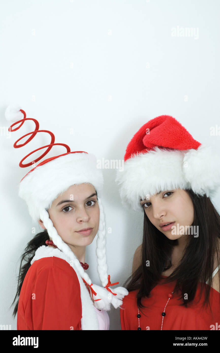 Due giovani amici di sesso femminile vestito in costumi di Natale, evidenti in telecamera, ritratto Foto Stock