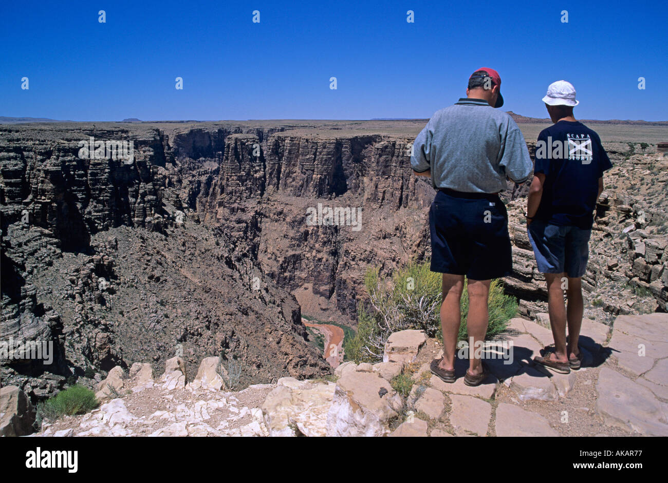 Due persone in piedi sul bordo di una gola rientra in una serie di canyon vicino al Grand Canyon con il Fiume Colorado al di sotto di Foto Stock