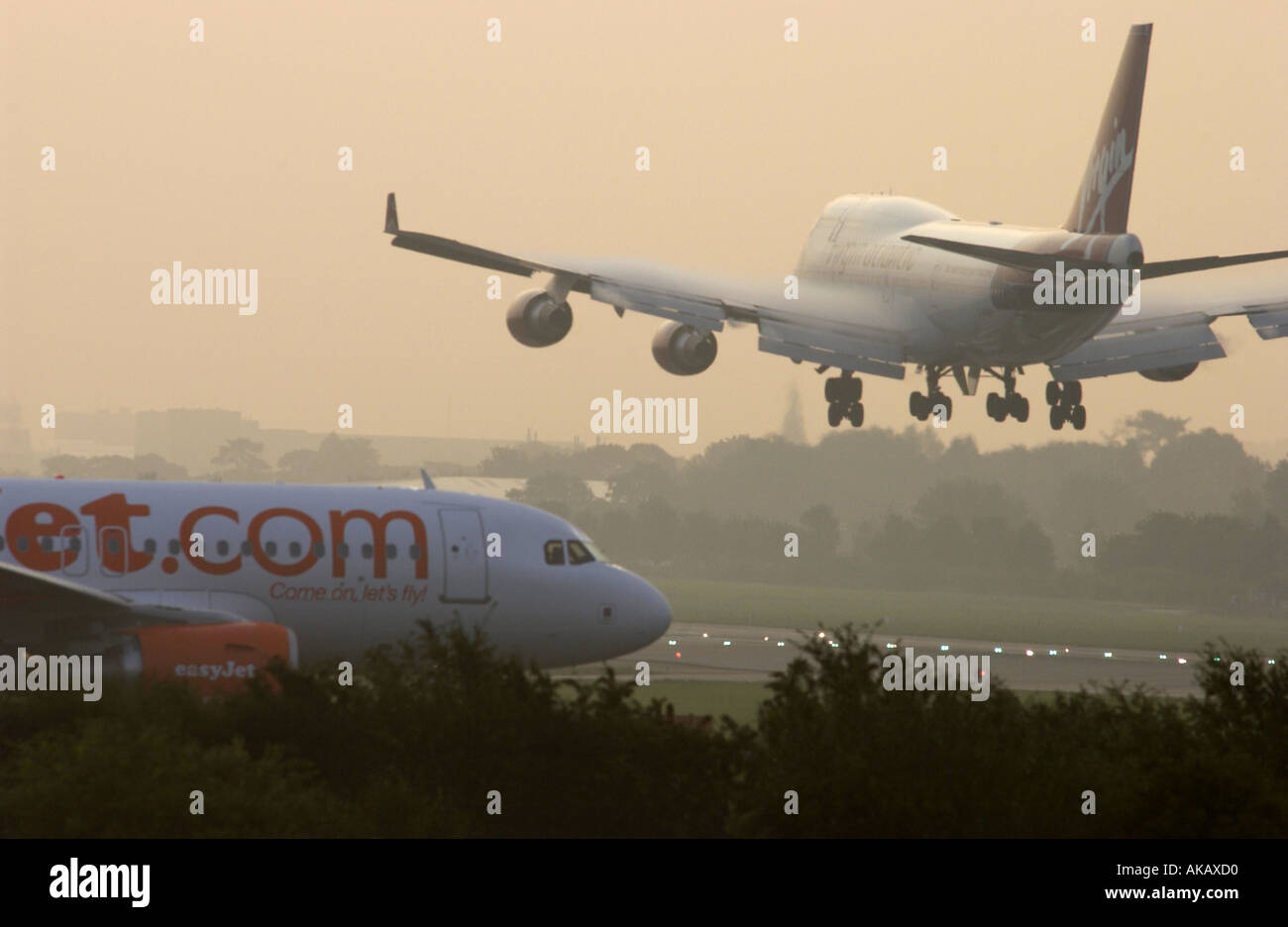 Un Virgin Atlantic Airways Boeing 747 Jumbo Jet entra in terra a Gatwick all'alba oltre un semplice piano di getto in attesa di decollo Foto Stock