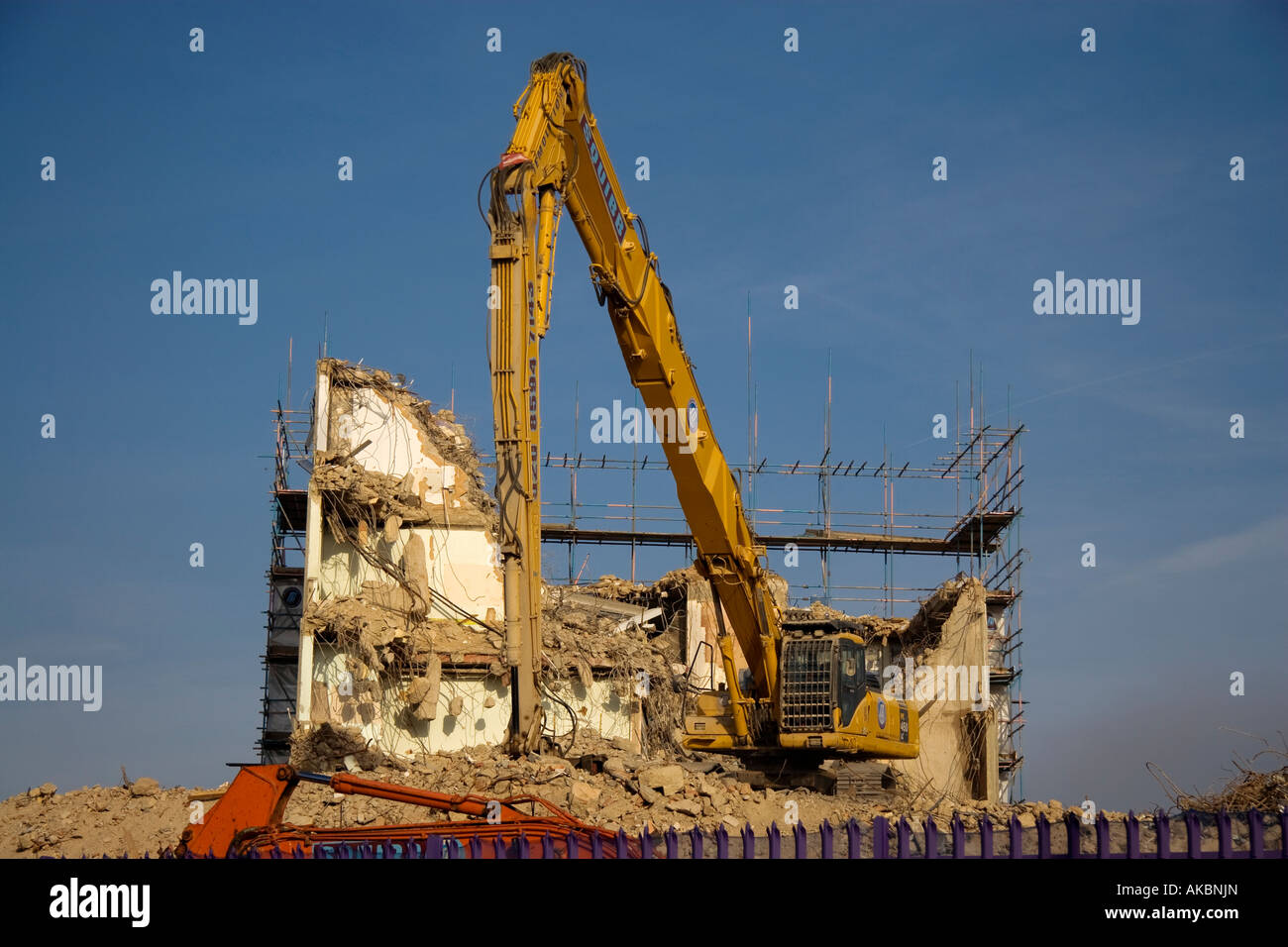Un escavatore giallo la demolizione di un edificio a Hackney Londra Foto Stock