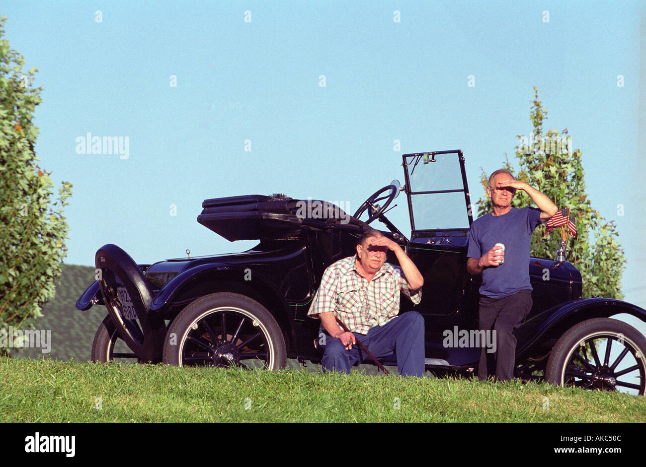 Due vecchi uomini seduti davanti ad un antico auto shading il sole dai loro occhi Foto Stock
