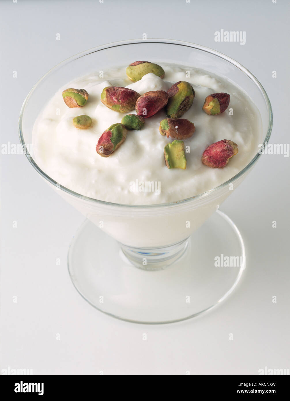 Una ciotola di vetro di pianura yogurt naturale con pistacchi vegetariano sano cibo editoriale Foto Stock