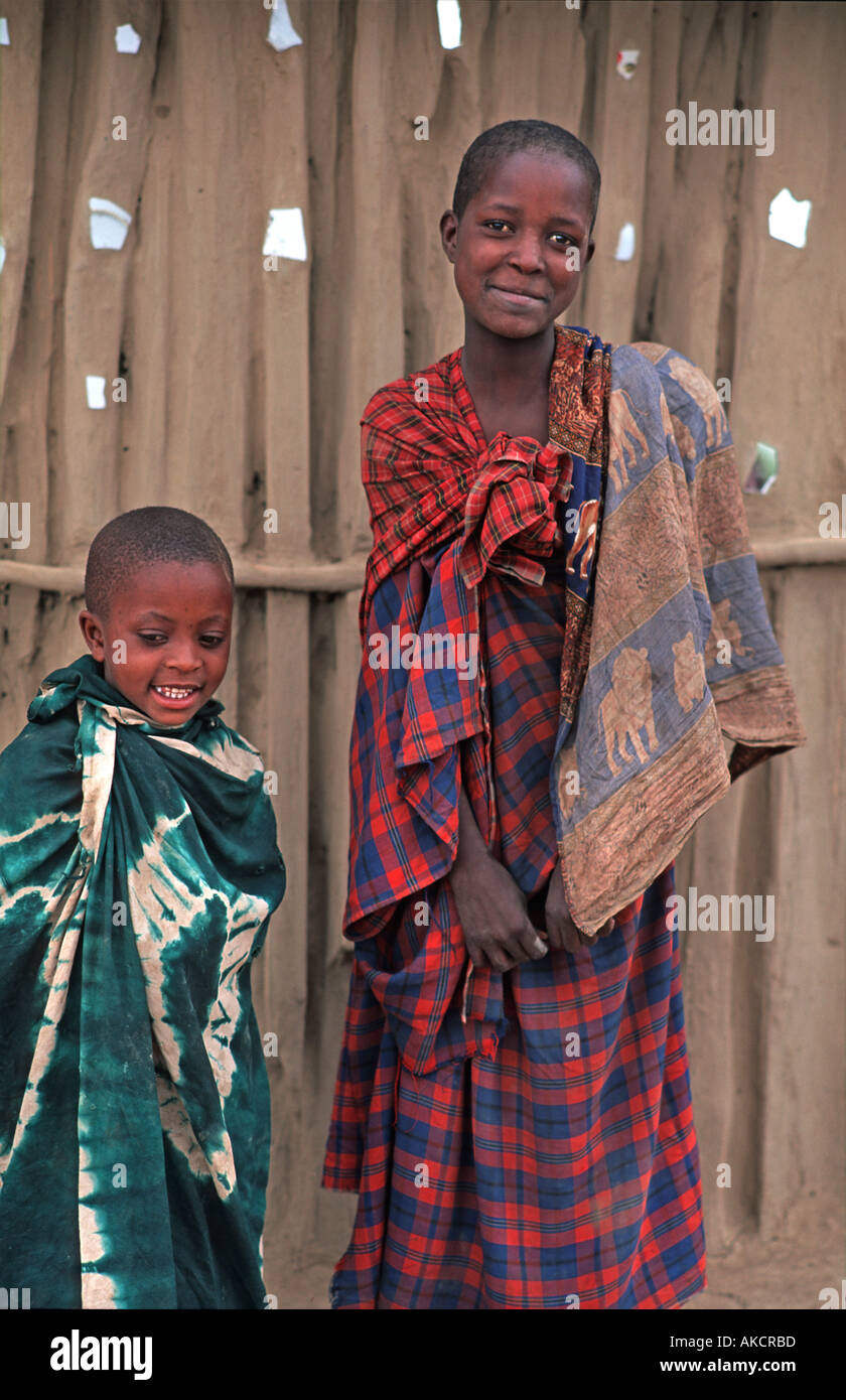 Masai bambini avvolti in tessuti al di fuori del loro fango e legno home N di Arusha in rotta verso S Kenya Tanzania Foto Stock