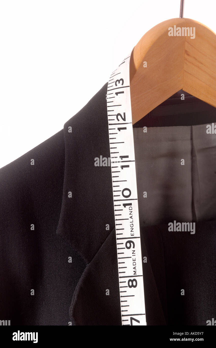 Primo piano di una giacca nera appesa su un appendiabiti in legno, con un metro a nastro avvolto sul colletto. Foto Stock
