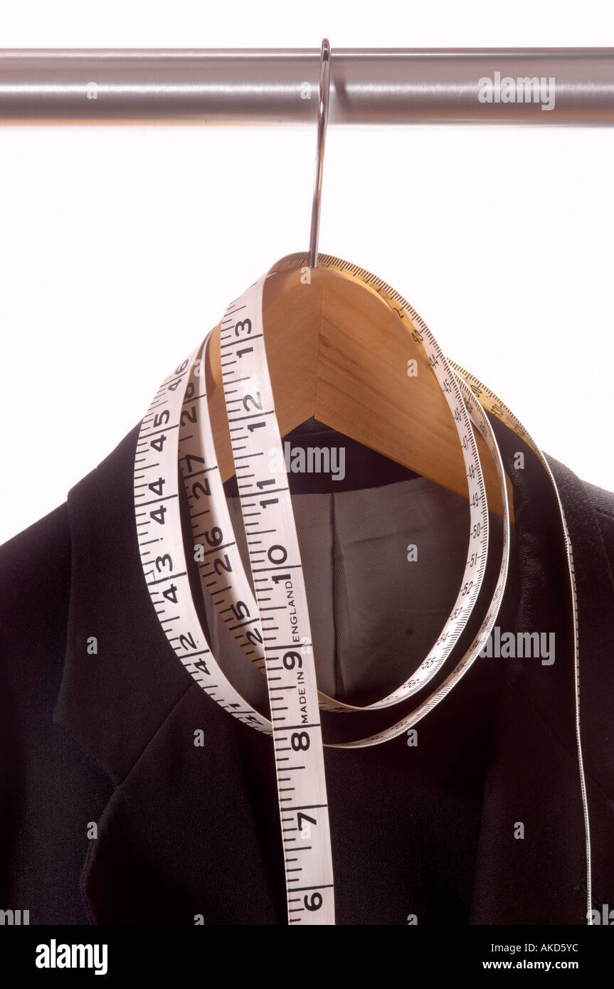 Giacca nera appesa su un appendiabiti in legno, su una guida in metallo con un metro a nastro avvolto intorno all'appendiabiti Foto Stock