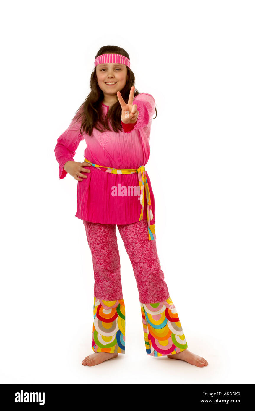 Ragazza sorridente in un vestito hippie, una mano sulla sua anca e l'altra che fa un segno di pace con un gesto a V. Foto Stock