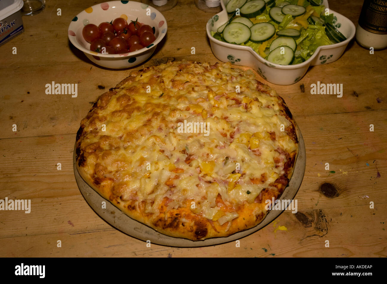 Tutto fresco home pizza cotta su piastra di pietra sul tavolo di pino Costwolds REGNO UNITO Foto Stock