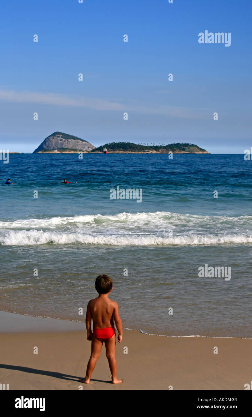 Bambino guardando il mare e il surfer bella spiaggia di Ipanema a Rio de Janeiro in Brasile Foto Stock