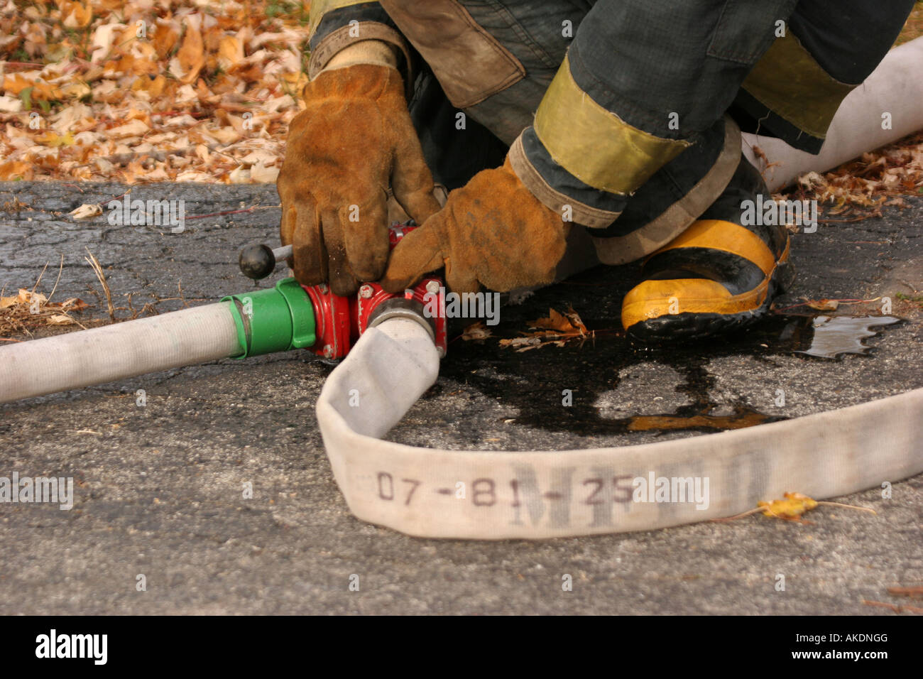 Un incendio fighter ai comandi di una valvola Y su un hoseline per la fornitura di acqua per altri vigili del fuoco sulla scena di emergenza Foto Stock