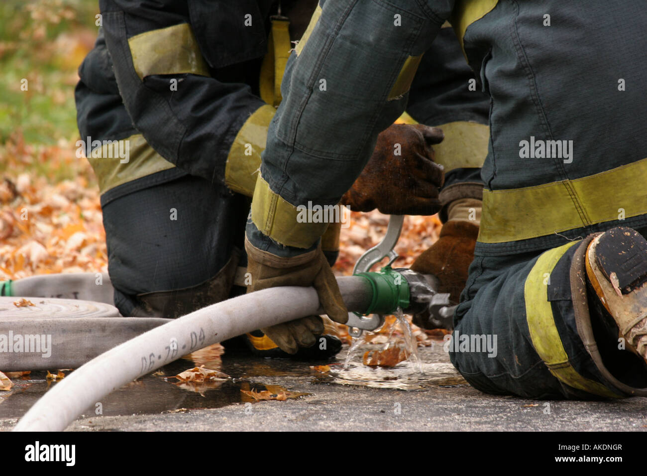 Due vigili del fuoco utilizza strumenti per serrare il raccordo del tubo flessibile perché è stato perde Foto Stock