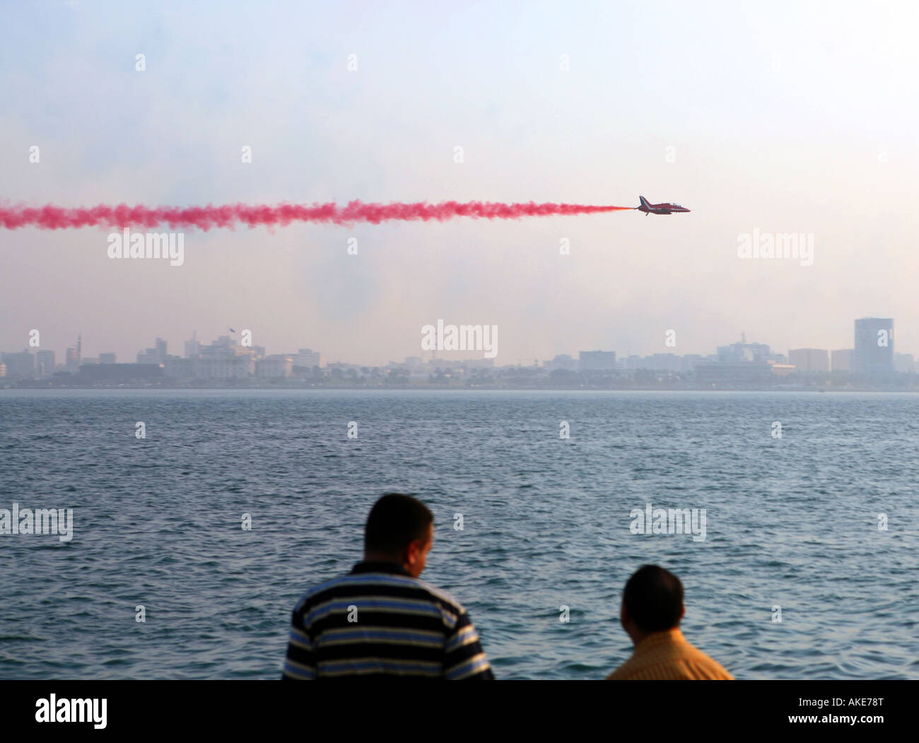 Lavoratori espatriati guardare come un membro delle frecce rosse RAF display team vola nella parte anteriore del Qatar s Emiri Diwan (dominatore's palace) Foto Stock