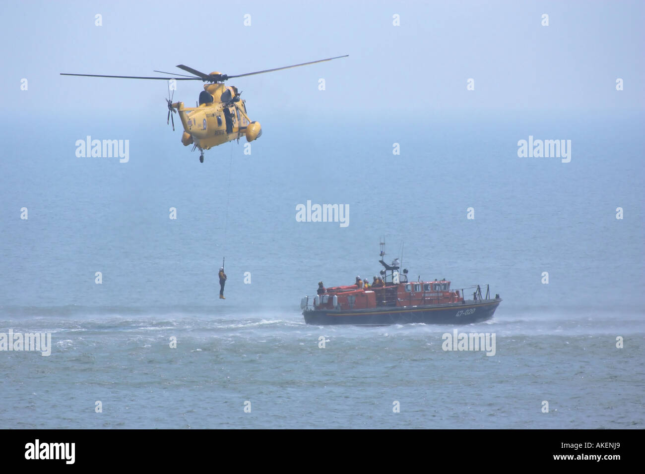 Un mare di RAF Re Salvataggio in elicottero winching su un RNLI scialuppa di salvataggio Foto Stock