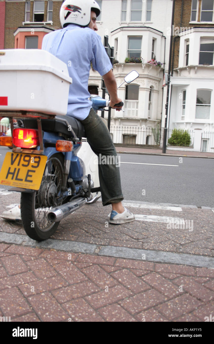 Uomo di consegna su uno scooter in attesa Foto Stock