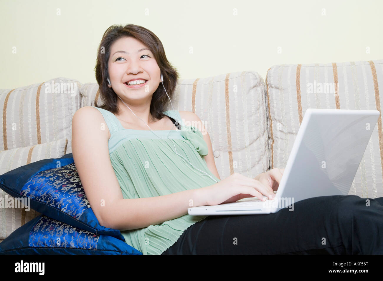 Giovane donna che utilizza un computer portatile e sorridente Foto Stock